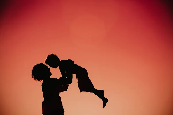 Ojciec i mały syn sylwetki grać na zachodzie słońca — Zdjęcie stockowe