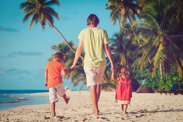 Vader en twee kinderen walking op strand — Stockfoto