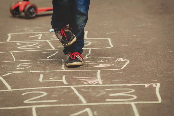 Pequeno menino jogar hopscotch no playground — Fotografia de Stock