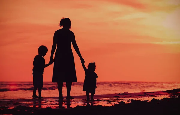 Mother and two kids walking on beach at sunset — Stock Photo, Image