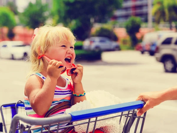 Achats avec des enfants- petite fille assis dans le panier demandant des achats — Photo