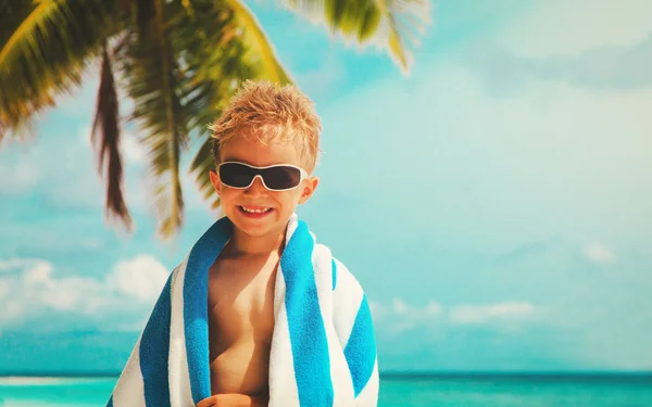 Onnellinen pieni poika kääritty pyyhe rannalla — kuvapankkivalokuva