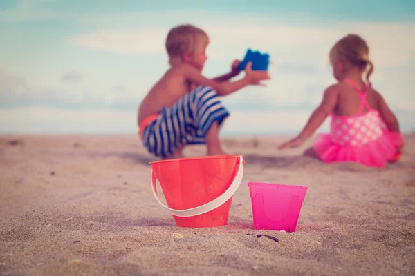 Little boy and girl play with sand at beach — Stock Photo, Image