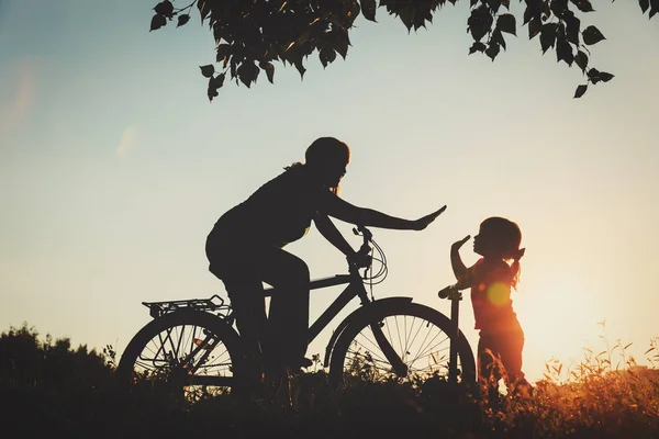Mãe e filha andando de bicicleta e scooter ao pôr do sol — Fotografia de Stock