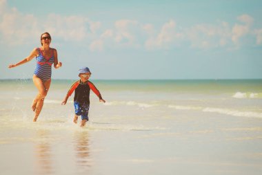 Anne ve oğlu kumsalda suda çalışan