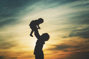 Baba ve küçük kızı gün batımında oynuyorlar.