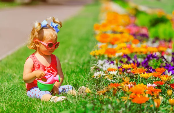Pequena menina regando flores no jardim — Fotografia de Stock