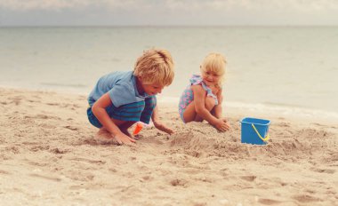 Küçük erkek ve kız yaz sahilde kum ile oynamak