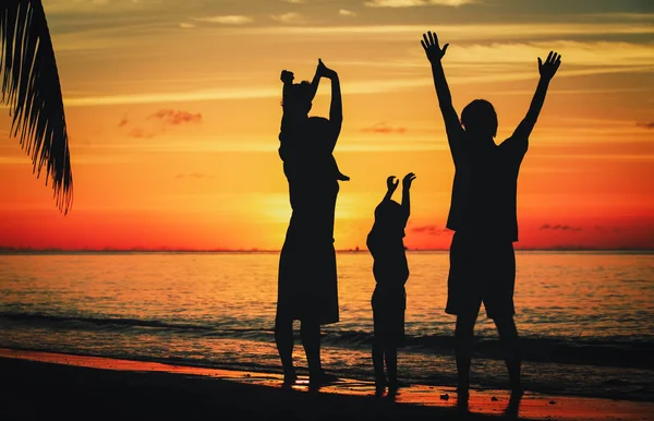 Famiglia felice con due bambini sulla spiaggia al tramonto — Foto Stock