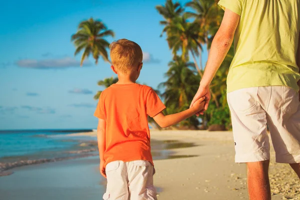 Отец и маленький сын держатся за руки на пляже — стоковое фото