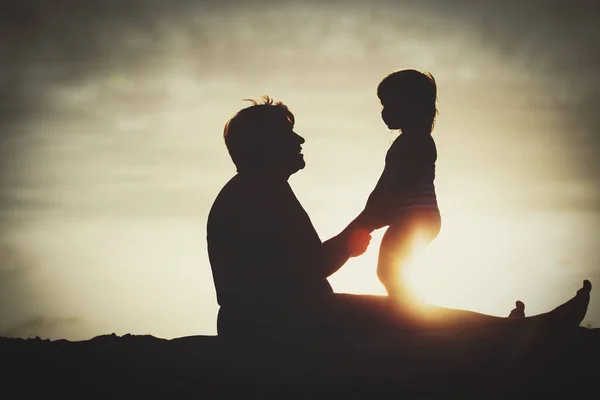 Silhouette of grandmother and little granddaughter play at sunset — Stock Photo, Image