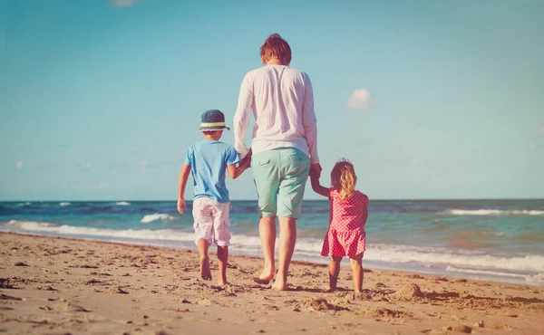 Padre y dos niños caminando en la playa — Foto de Stock