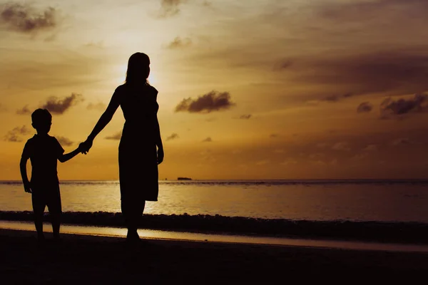 Мать и сын гуляют по пляжу на закате — стоковое фото