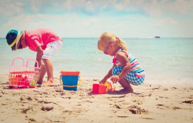 Çocuklar yaz plajında kumla oynarlar.