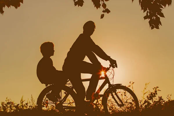 Батько з сином катається на велосипедах на заході сонця — стокове фото