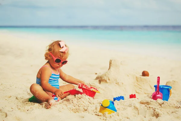 Cute little girl playing with sand on beach — Stock Photo, Image