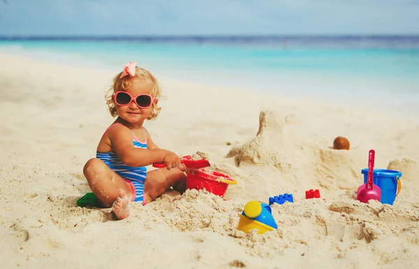 Cute little girl playing with sand on beach — Stock Photo, Image