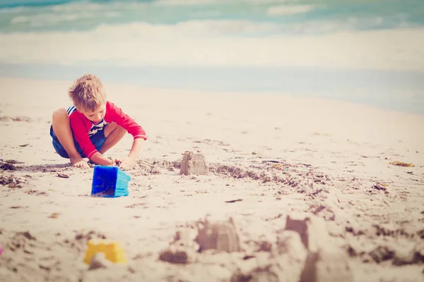 Kleine jongen spelen met zand op zomerstrand — Stockfoto
