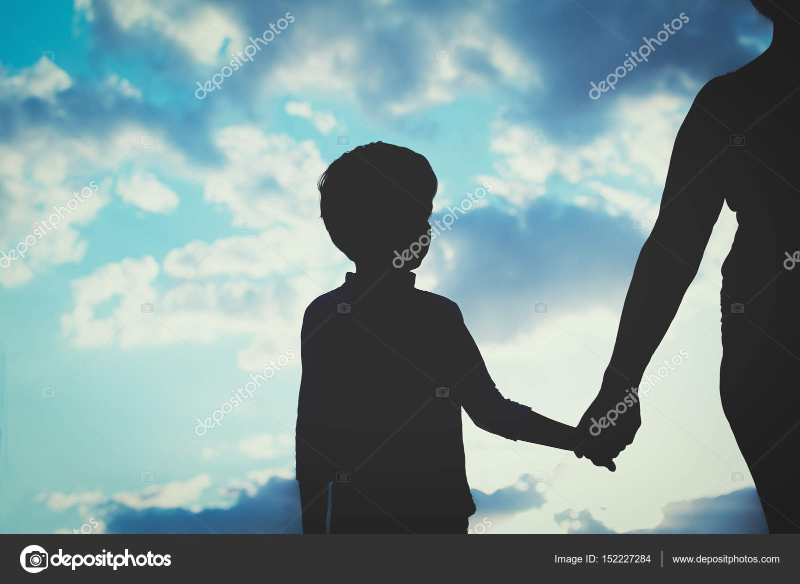 Silhouette Of Mother And Son Holding Hands At Sunset Stock Photo