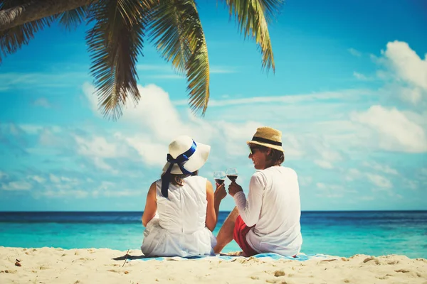 Счастливая любящая пара пьет вино на пляже — стоковое фото
