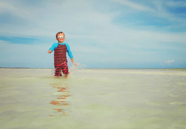 Niño pequeño disfrutar jugar con el agua en la playa —  Fotos de Stock