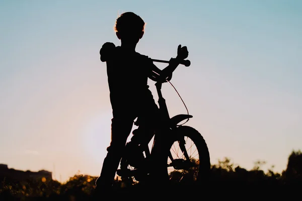 Маленький хлопчик їде на велосипеді на заході сонця, дитячий спорт — стокове фото
