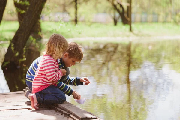 Niño y niña jugando con barcos de papel en la naturaleza — Foto de Stock
