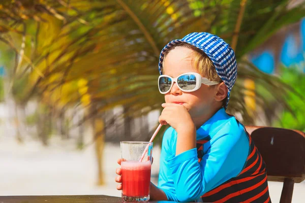 Bonito menino bebendo suco na praia tropical — Fotografia de Stock