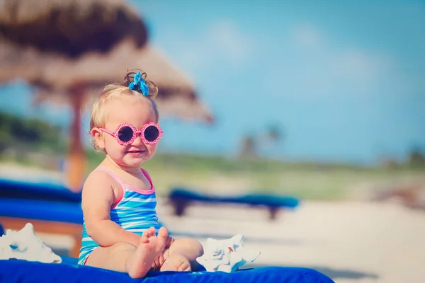 Roztomilá holčička hrát s mušle na pláži — Stock fotografie