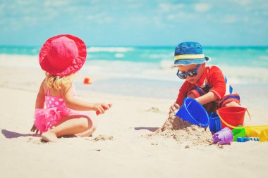 Çocuklar yaz plajında kumla oynarlar.