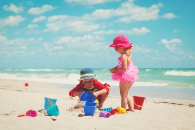 Çocuklar yaz plajında kumla oynarlar.