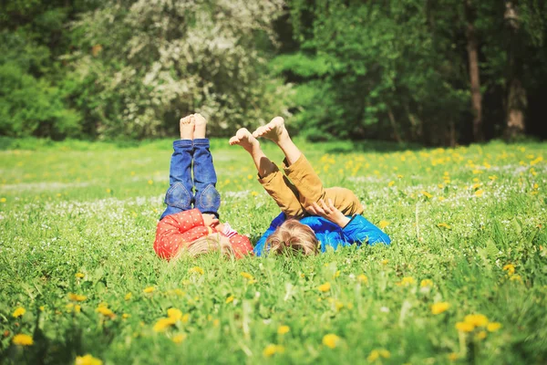 Liten pojke och flicka koppla av på grönt gräs — Stockfoto