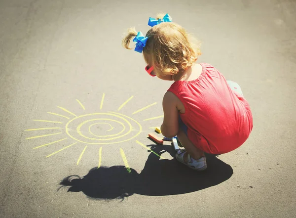 Dziewczynka rysunek słońce na asfalcie — Zdjęcie stockowe