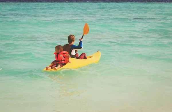Отец и маленький сын катаются на байдарках в море — стоковое фото