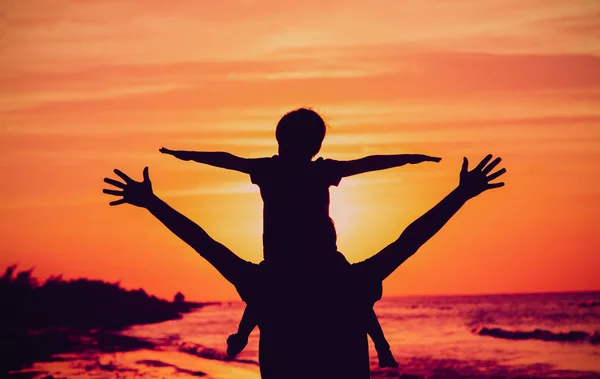 Pai e filho brincam na praia do pôr do sol — Fotografia de Stock