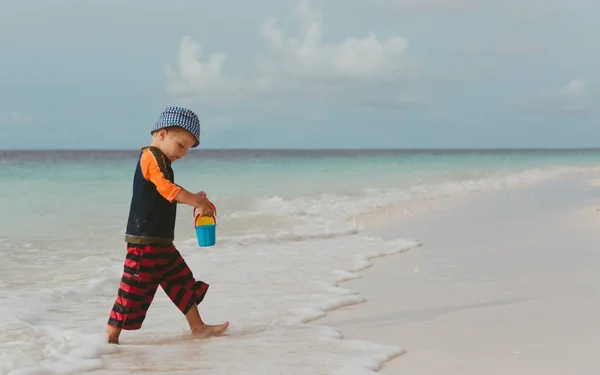 Kleine jongen spelen met water op het strand — Stockfoto