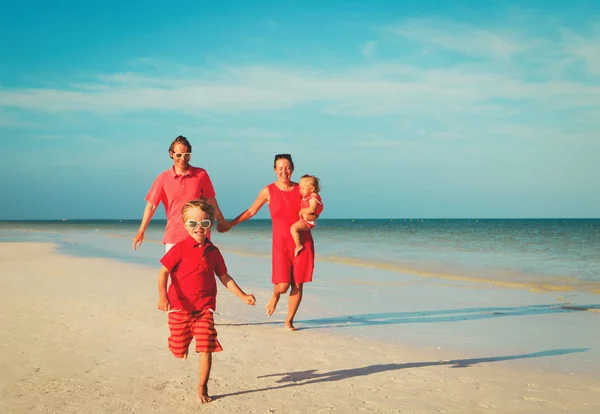 Familia feliz con dos niños corren en la playa — Foto de Stock