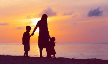 Anne ve iki çocuğu batımında sahilde yürüyüş
