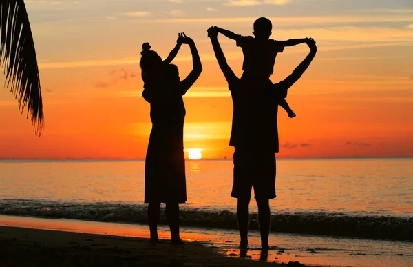 Família feliz com duas crianças na praia do por do sol — Fotografia de Stock