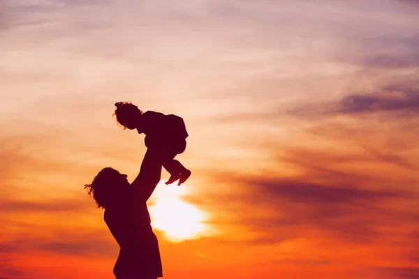 Pai e pequena filha silhuetas jogar ao pôr do sol — Fotografia de Stock