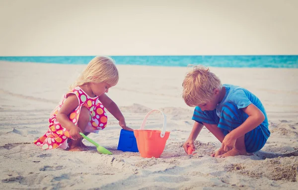 Kleine jongen en meisje spelen met zand op het strand — Stockfoto