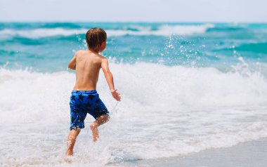küçük çocuk oyun ile dalgalar kumsalda çalıştırın.