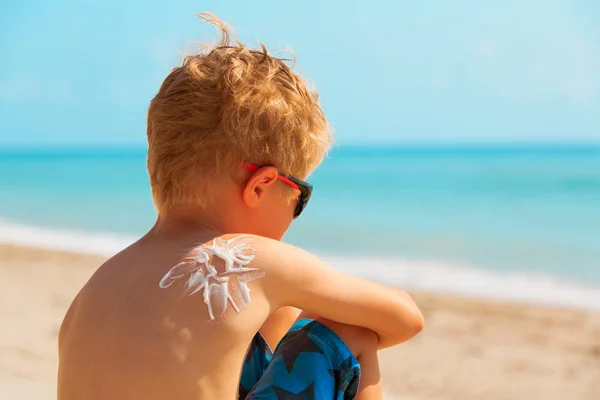 Protección solar - niño pequeño con crema solar en el hombro en la playa — Foto de Stock