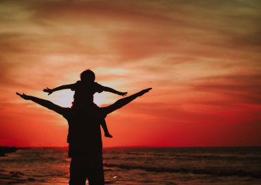 Baba ve küçük oğlu günbatımı plaj üzerinde oynamak