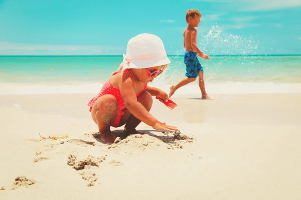 Little boy and girl play with sand on beach — Stock Photo, Image
