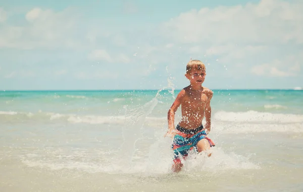 Felice ragazzo correre giocare con le onde sulla spiaggia — Foto Stock