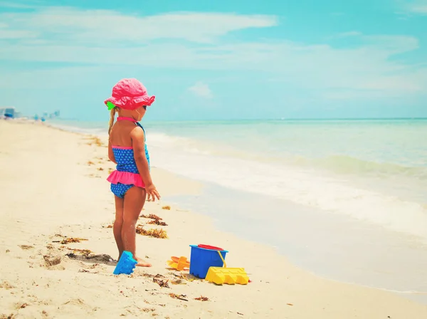 Милая маленькая девочка играет с песком на пляже — стоковое фото