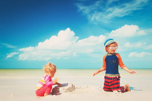 Mały chłopiec i dziewczyna grać z piaskiem na plaży — Zdjęcie stockowe
