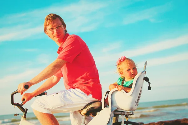 Padre e figlia piccola in bicicletta sulla spiaggia — Foto Stock