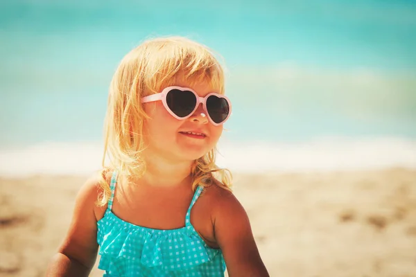 Защита от солнца - маленькая девочка с кремом для загара на пляже — стоковое фото